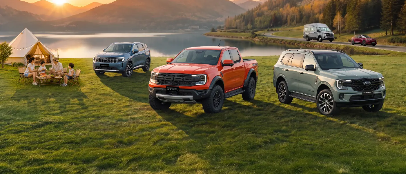 Bốn chiếc xe bán tải và SUV của Ford đang đỗ trên một bãi đất trống dưới bầu trời nhiều mây, phô diễn các mẫu mã và màu sắc đa dạng, bao gồm đỏ, xanh dương, bạc và nâu vàng.