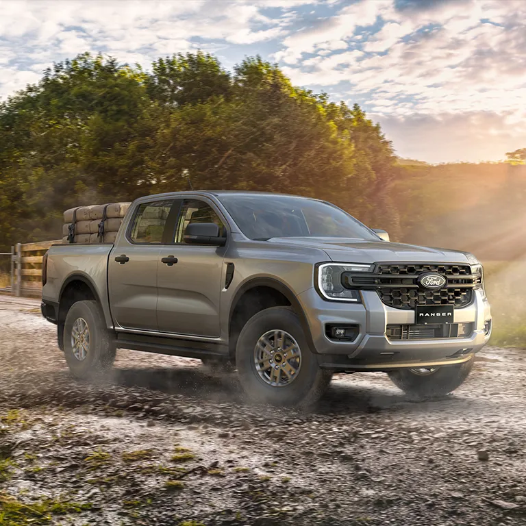 three quarter front angle shot of a metallic gray pickup with warm golden sunlight