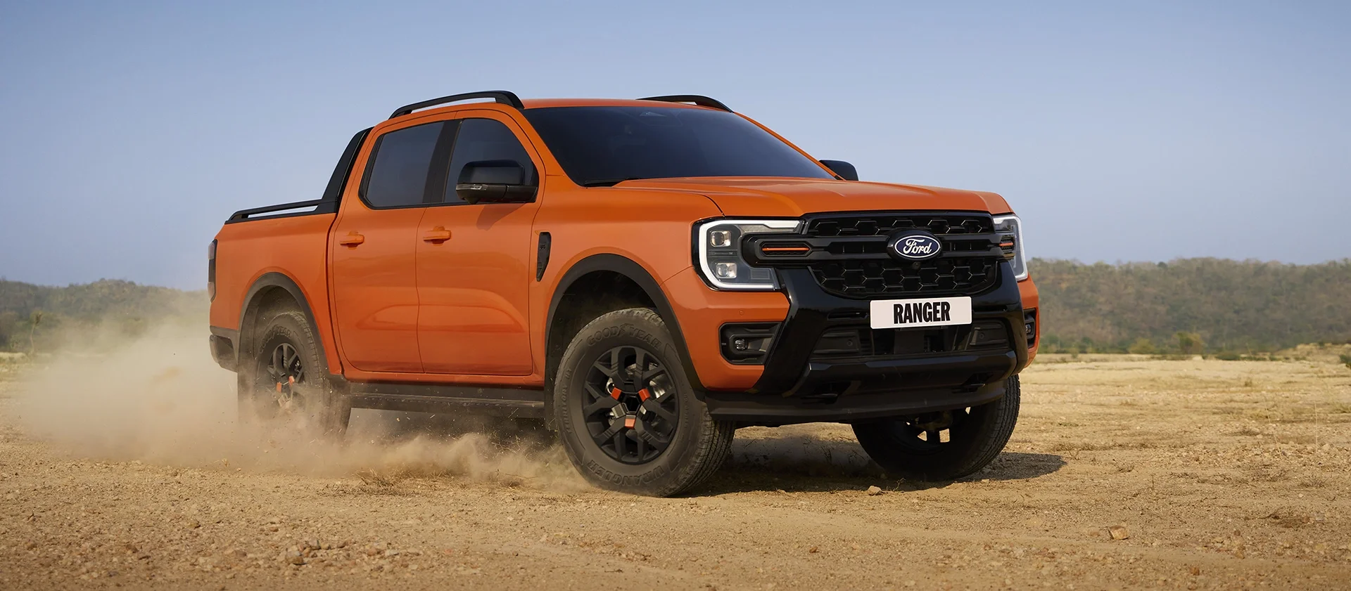Orange Ford Ranger driving on dusty terrain.